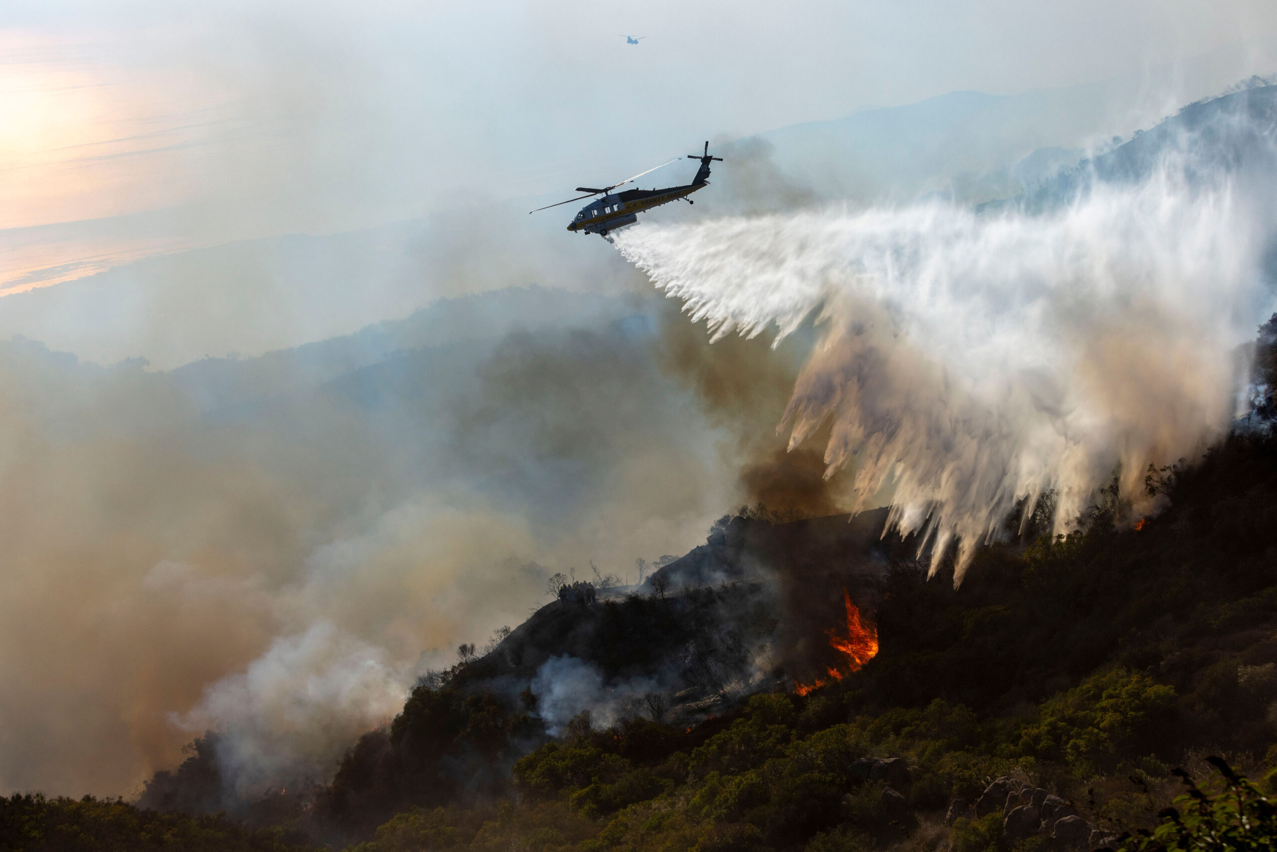 Ein Löschhubschrauber des Los Angeles County wirft Wasser auf das Feuer.