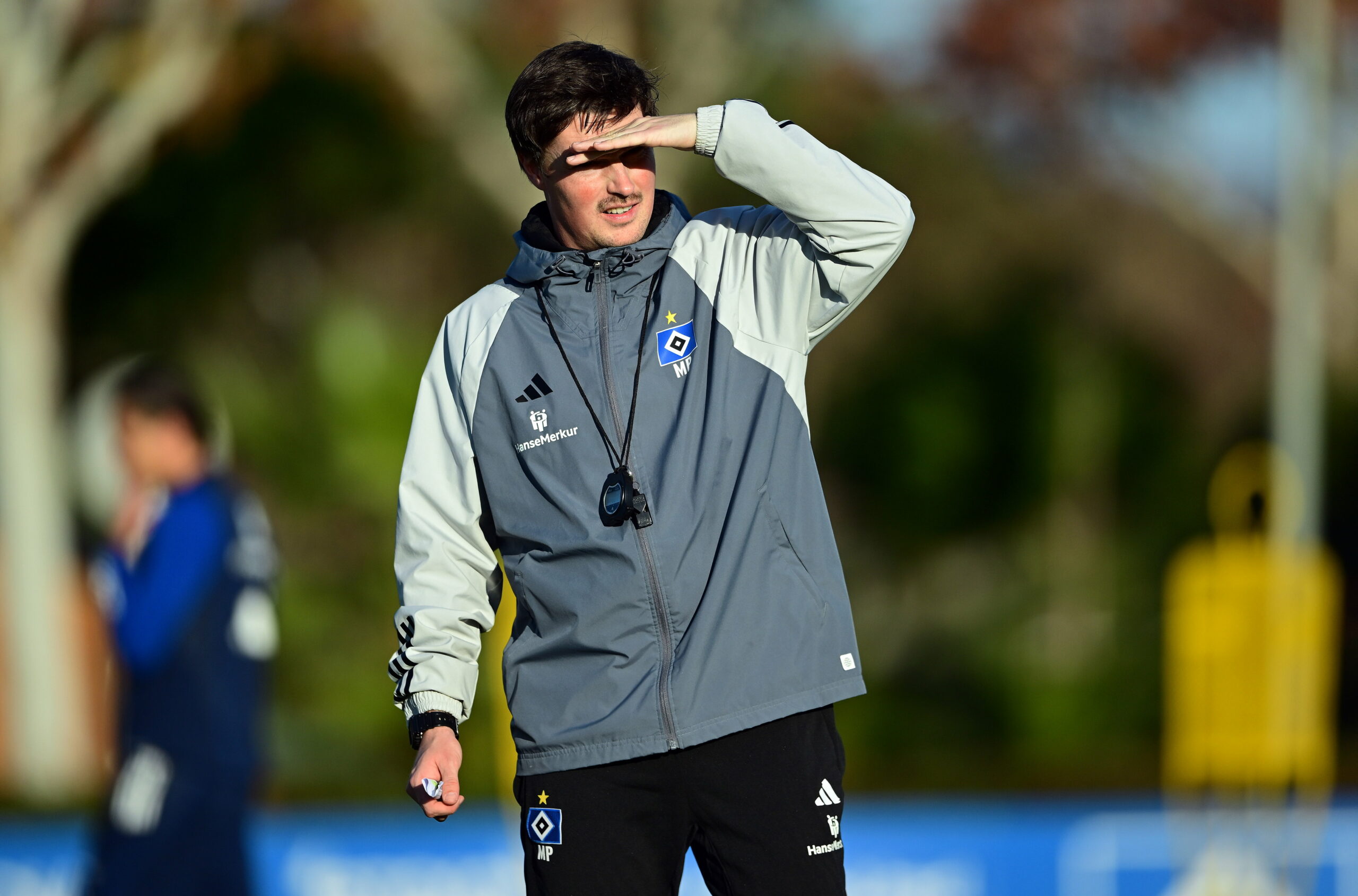 HSV-Traner Merlin Polzin hält die linke Hand als Sonnenschutz vor das Gesicht.