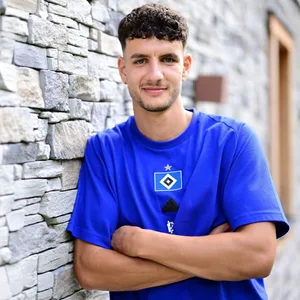 Daniel Elfadli lehnt mit verschränkten Armen an einer Wand
