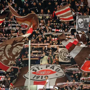 Fans in der Südkurve des Millerntors halten Schals in die Höhe und singen