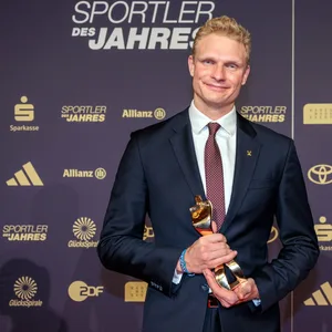 Oliver Zeidler lächelt mit Trophäe in der Hand
