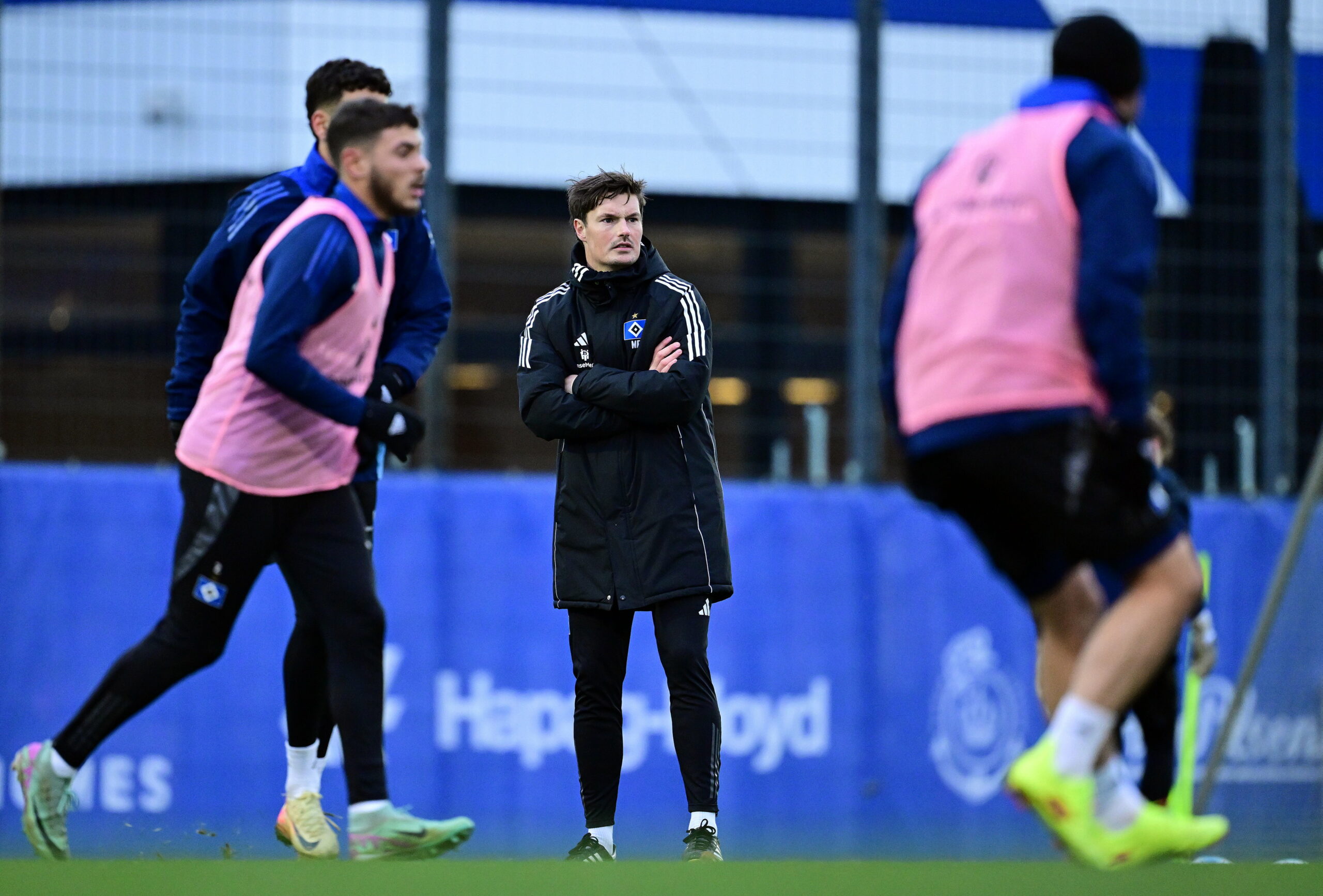 Merlin Polzin beobachten das HSV.Training mit verschränkten Armen.