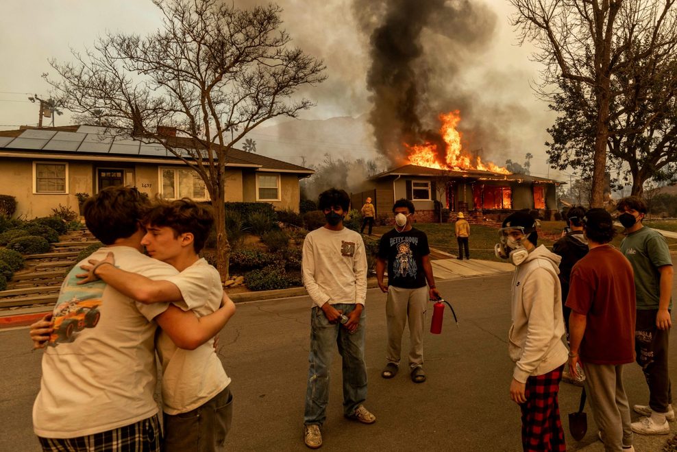 Anwohner von Altadena bei Los Angeles umarmen sich vor einem Haus, das vom Eaton-Feuer erfasst wurde.