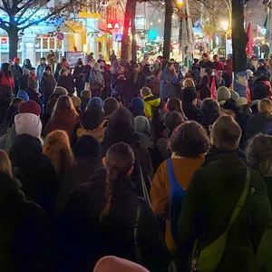 Vielen Menschen stehen auf einem Platz in Ottensen. im Hintergrund sind die Lichter der Läden.
