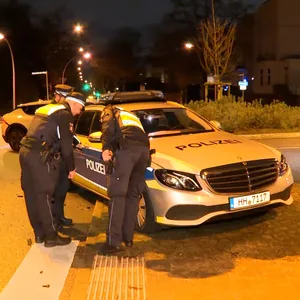 Polizisten begutachten einen beschädigten Streifenwagen