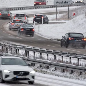 Pkw fahren auf einem verschneitem Autobahnzubringer.