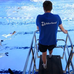 Ein Fachangestellter für Bäderbetriebe (FBB) bei der Badeaufsicht der ersten Schwimmerinnen und Schwimmer in der umgebauten und erweiterten Alsterschwimmhalle.