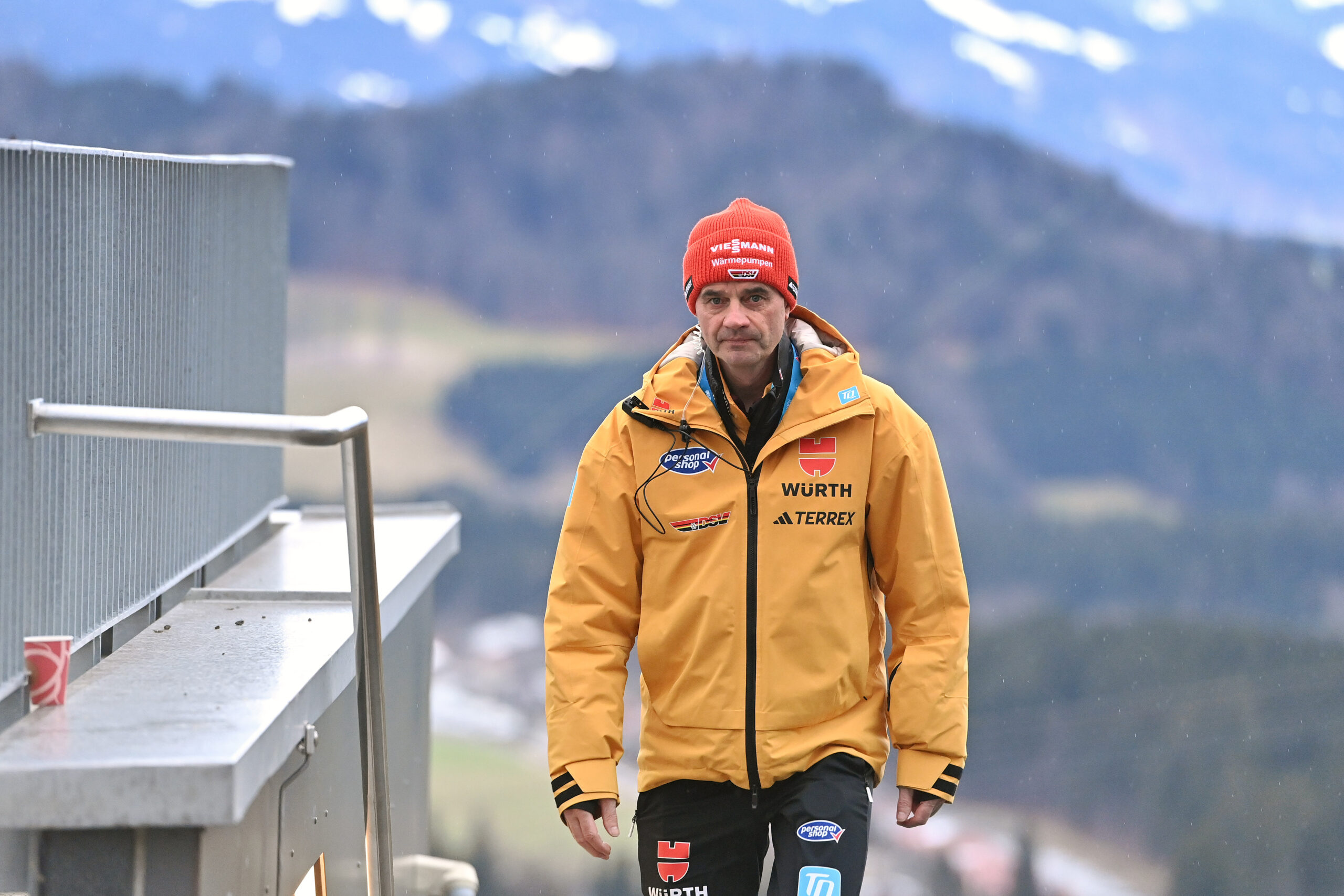 Stefan Horngacher geht eine Treppe an einer Skisprungschanze hoch