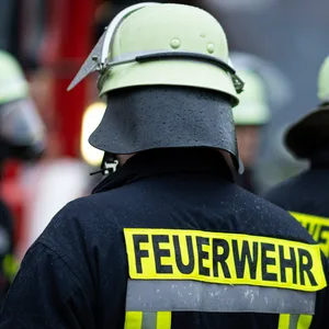 Feuerwehrmänner mit Feuerwehrhelm und dem Schriftzug Feuerwehr auf der Schutzausrüstung.