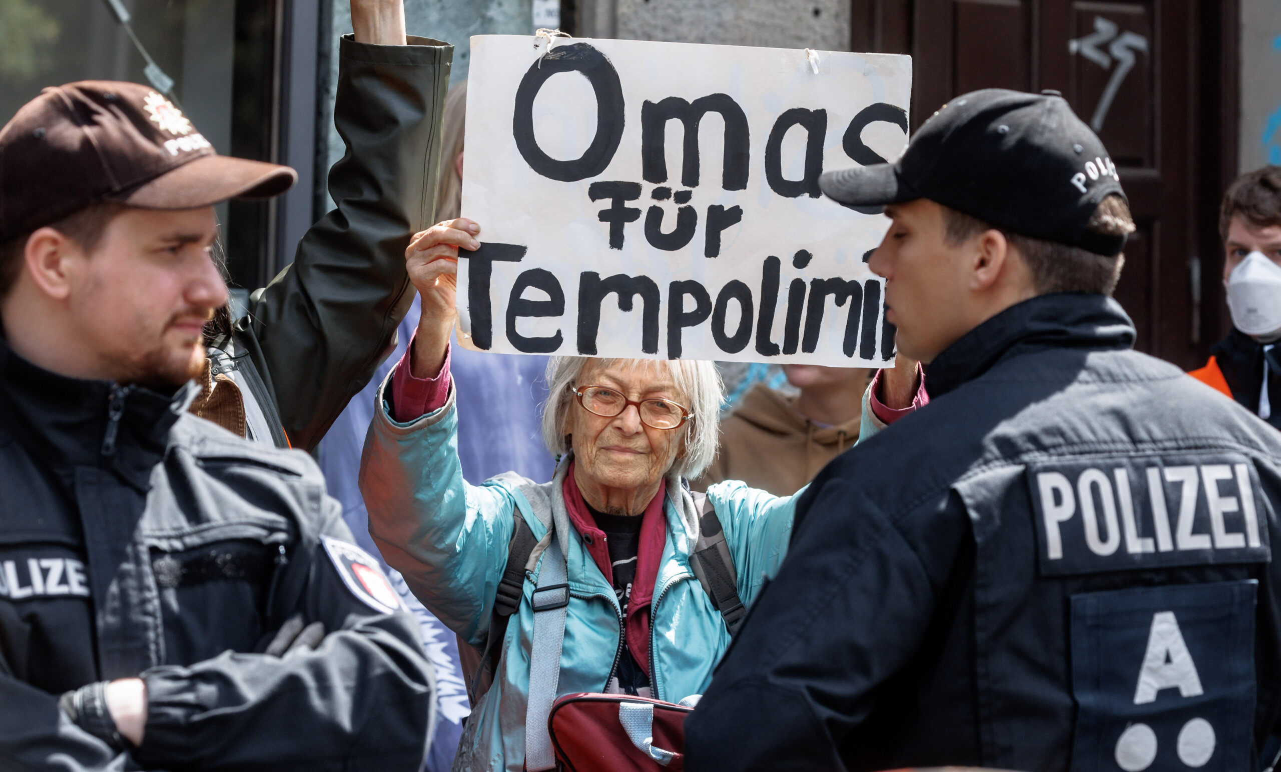 Eine alte Dame hält ein Schild hoch mit der Aufschrift „Omas für Tempolimit“