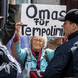 Eine alte Dame hält ein Schild hoch mit der Aufschrift „Omas für Tempolimit“