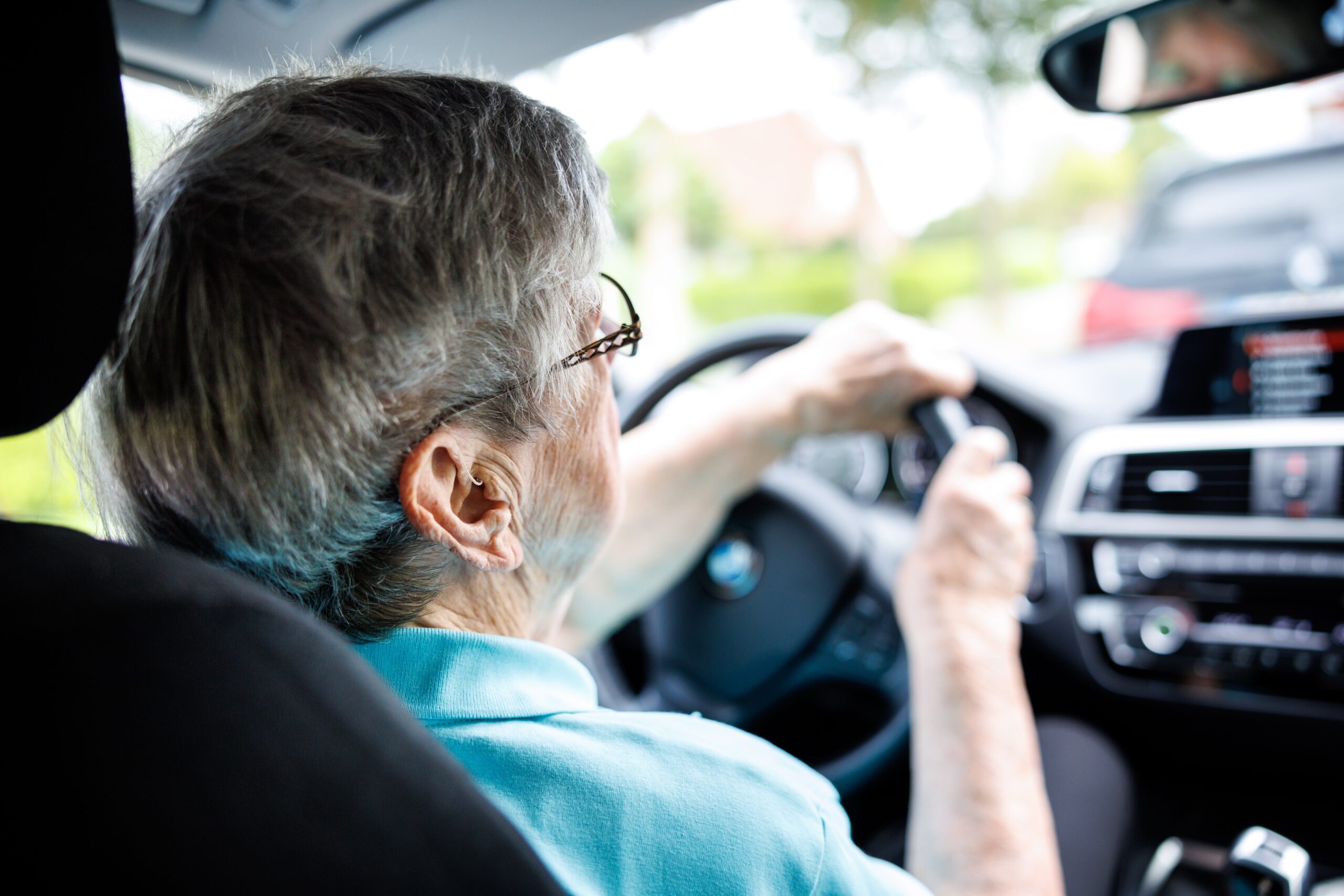 Eine Seniorin sitzt hinter dem Lenkrad eines Autos.