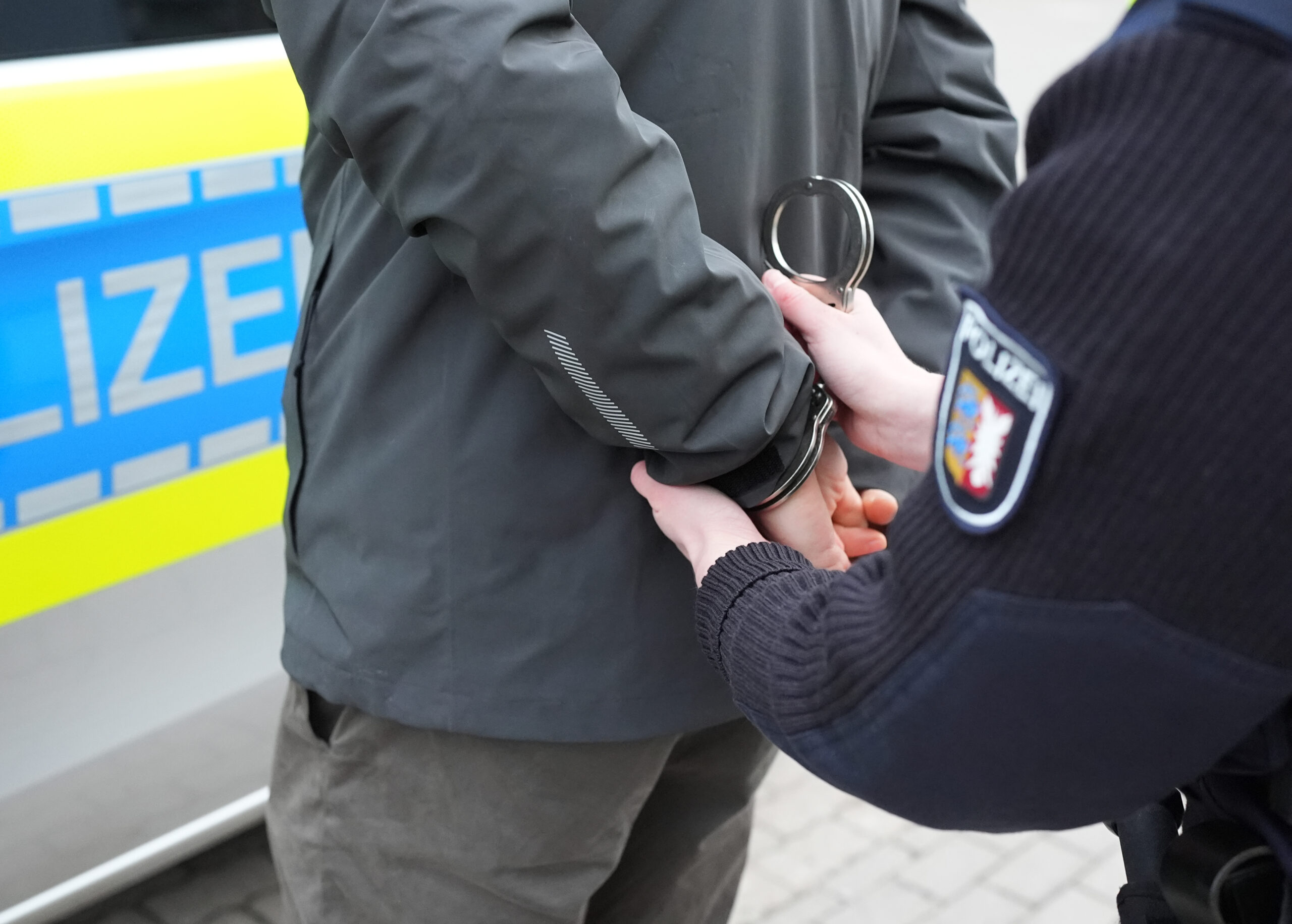 Eine Polizistin legt einem Mann Handschellen an.
