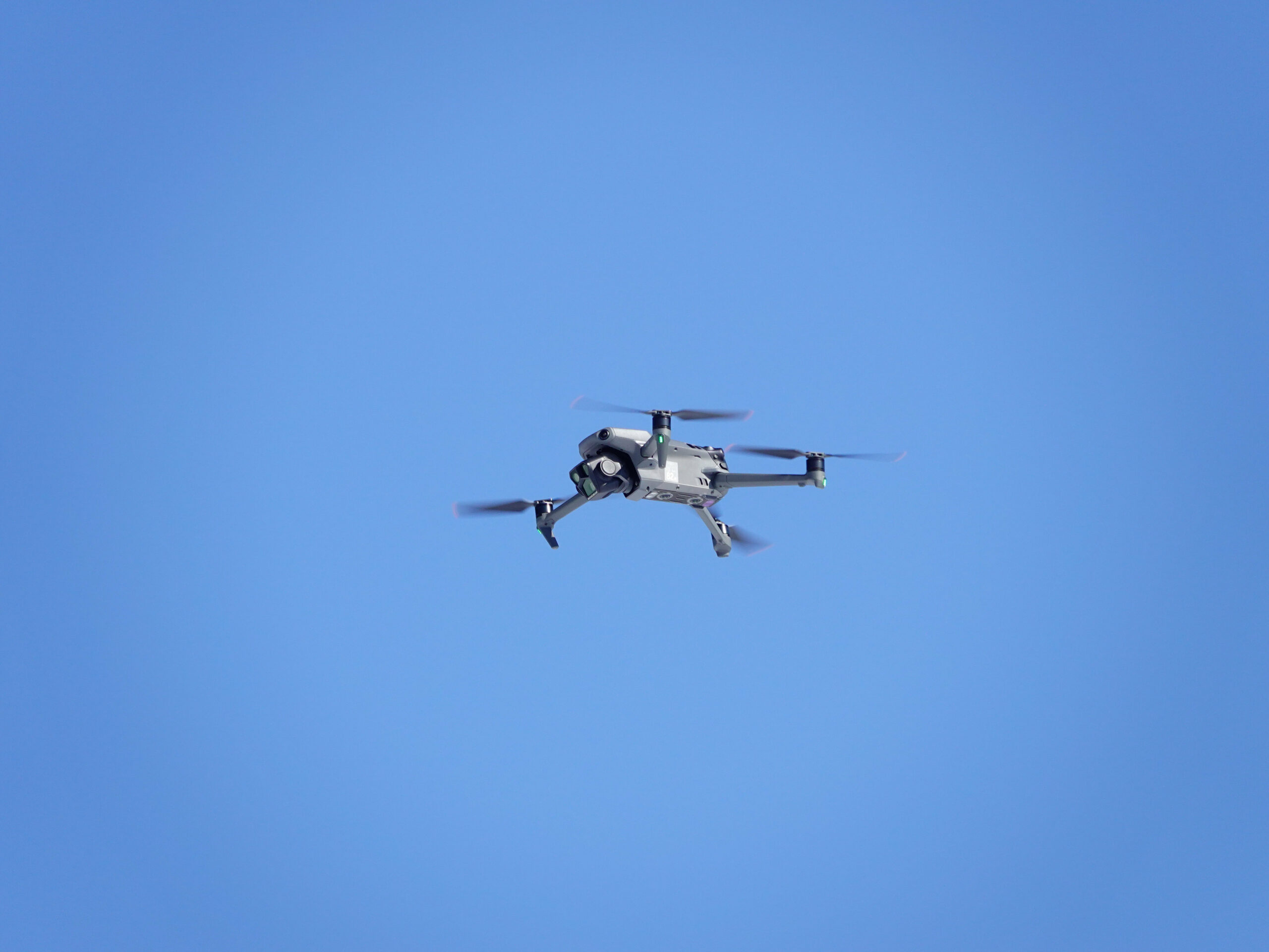 Eine Drohne fliegt im blauen, wolkenlosen Himmel und wird mit einem roten Kreis anvisiert