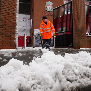 Ein Arbeiter schiebt Schnee vor der Anfield Road