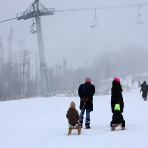 Eine Familie mit Schlitten läuft über den verschneiten Wurmberg im Harz.