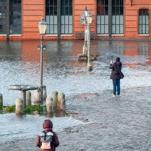 Passanten beobachten die erste Sturmflut des Jahres auf dem Hamburger Fischmarkt.