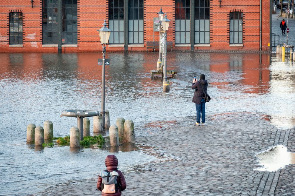 Passanten beobachten die erste Sturmflut des Jahres auf dem Hamburger Fischmarkt. 