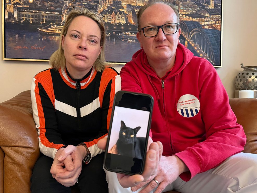 Catharina Majert und ihr Mann Gunnar zeigen auf einem Smartphone ein Foto ihrer Bombay-Katze Aramis.