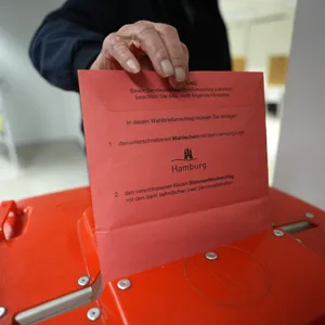 Ein Wähler steckt die Stimmzettel nach seiner Wahlabgabe in eine Wahlurne in der zentralen Briefwahlstelle zur Bürgerschaftswahl und Bundestagswahl 2025 auf dem Gerhart-Hauptmann-Platz.