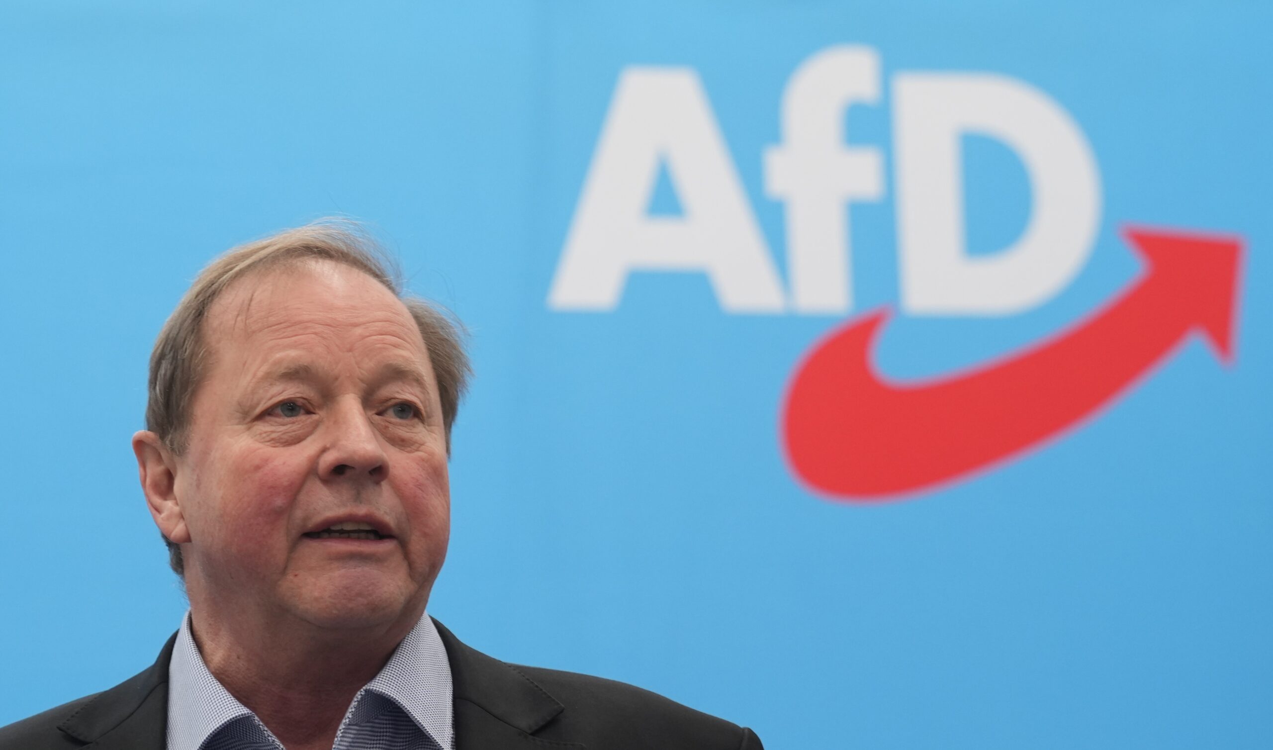 Dirk Nockemann, Landesvorsitzender der AfD Hamburg steht vor einem bauen Hintergrund mit AfD Logo