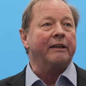 Dirk Nockemann, Landesvorsitzender der AfD Hamburg steht vor einem bauen Hintergrund mit AfD Logo