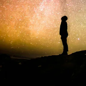 Die Silhouette einer Person, die in den Sternenhimmel schaut.