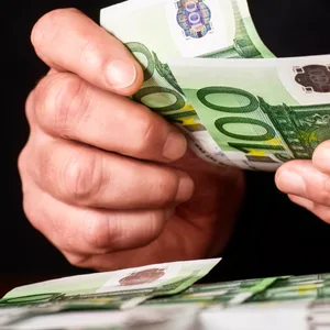 Hände mit 100-Euro-Geldscheinen