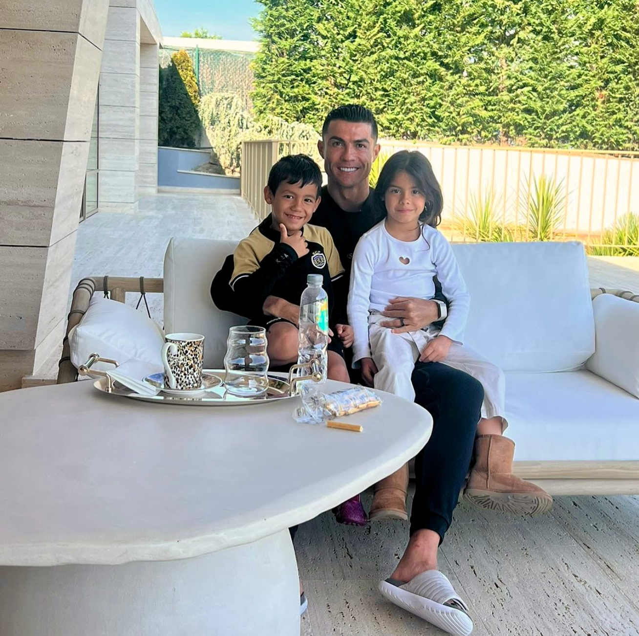 Cristiano Ronaldo sitzt mit zwei seiner Kinder draußen auf einem Sofa