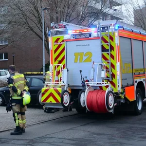 Polizei und Feuerwehr stehen vor einem Mehrfamilienhaus.