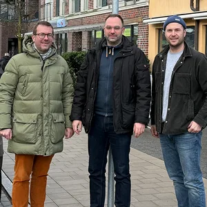 Drei Männer stehen unter einem „Ladezone“-Schild.