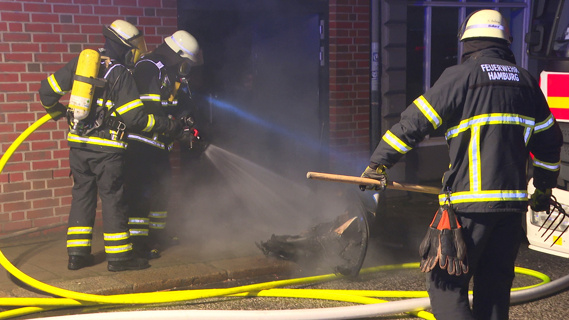 Feuerwehrleute löschen den verschmorten Müllcontainer.