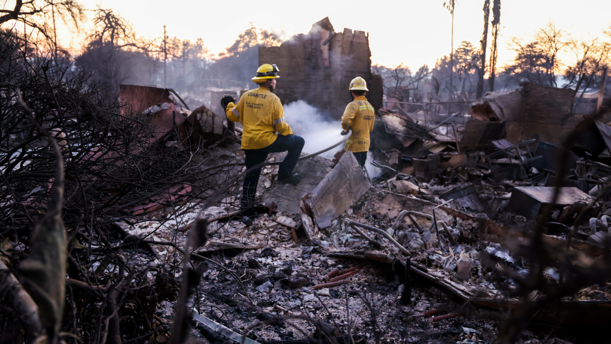 Feuerwehrleute arbeiten in den Trümmern der verbrannten Häuser in LA.