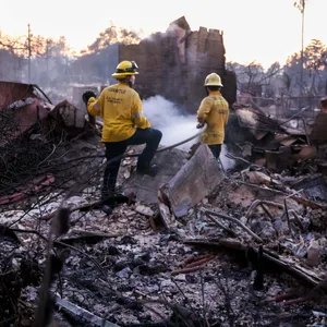 Feuerwehrleute arbeiten in den Trümmern der verbrannten Häuser in LA.