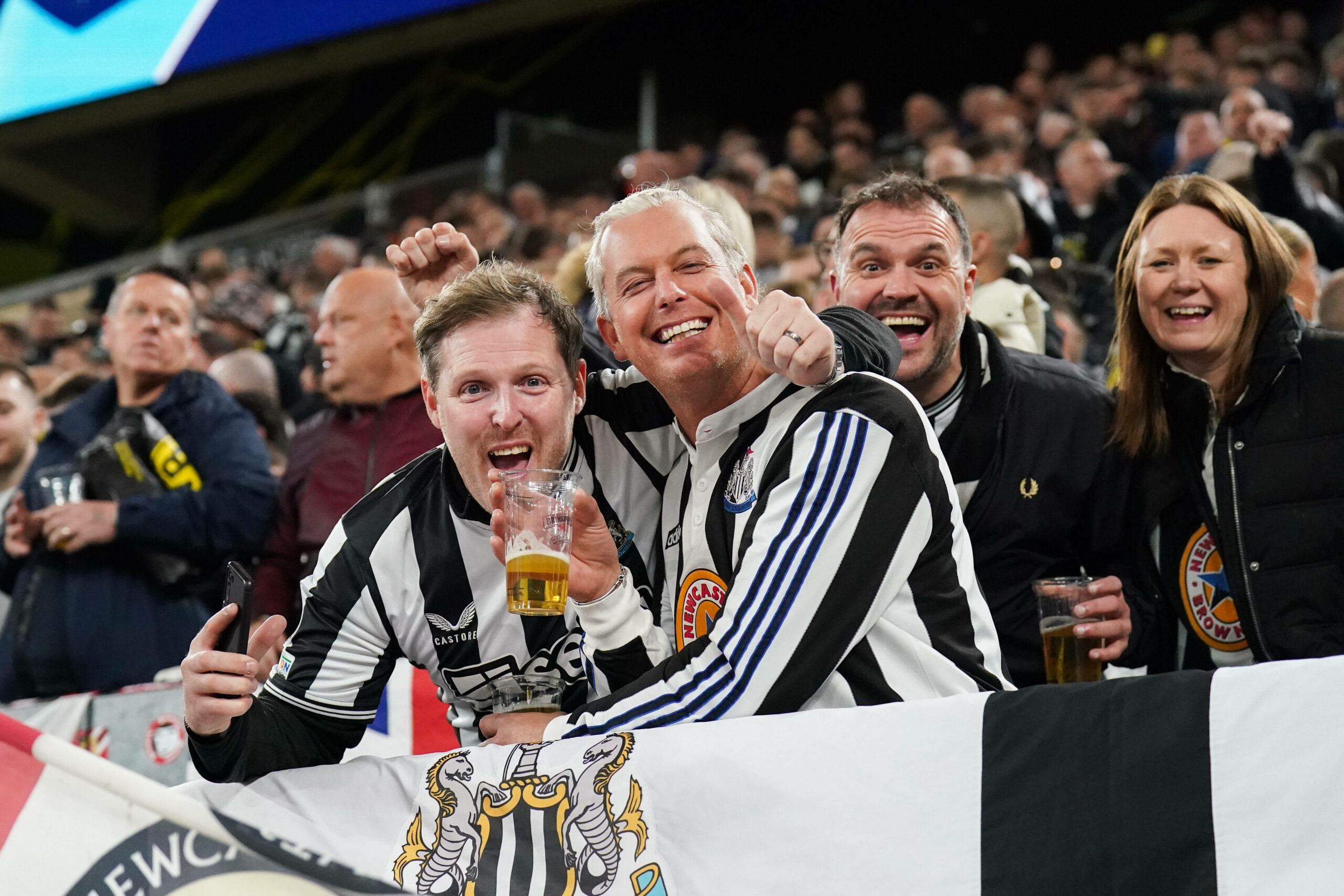 Newcastle Fans halten ein Bier und jubeln in die Kamera