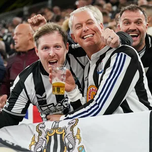 Newcastle Fans halten ein Bier und jubeln in die Kamera