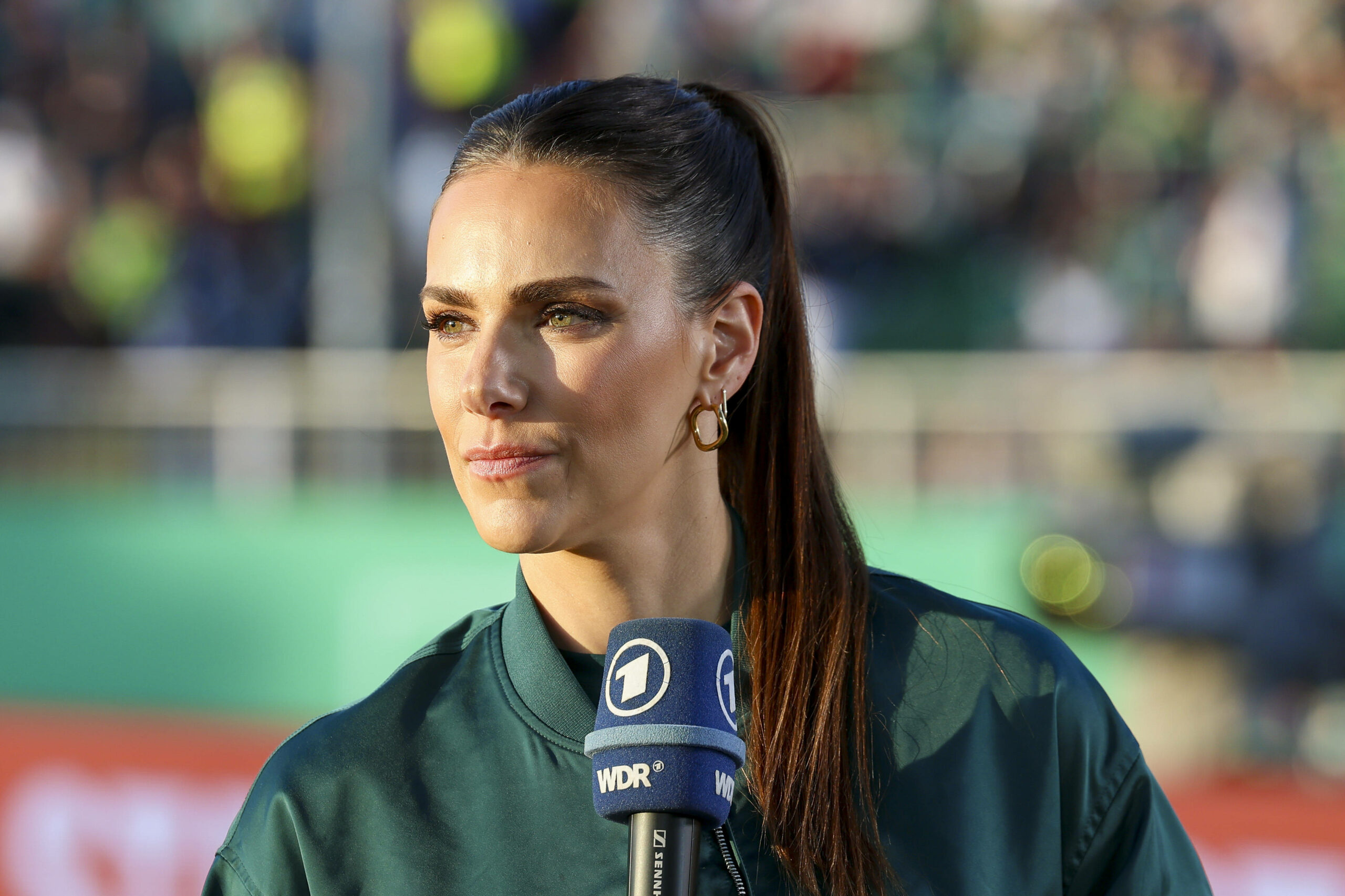 Esther Sedlaczek mit einem Sportschau-Mikrofon in der Hand