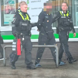 Ein Mann wird von drei Polizisten abgeführt