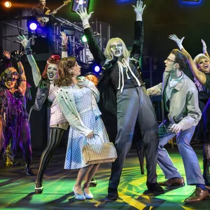 Darsteller der „Rocky Horror Show“ stehen in auffälligen Kostümen auf der Bühne.