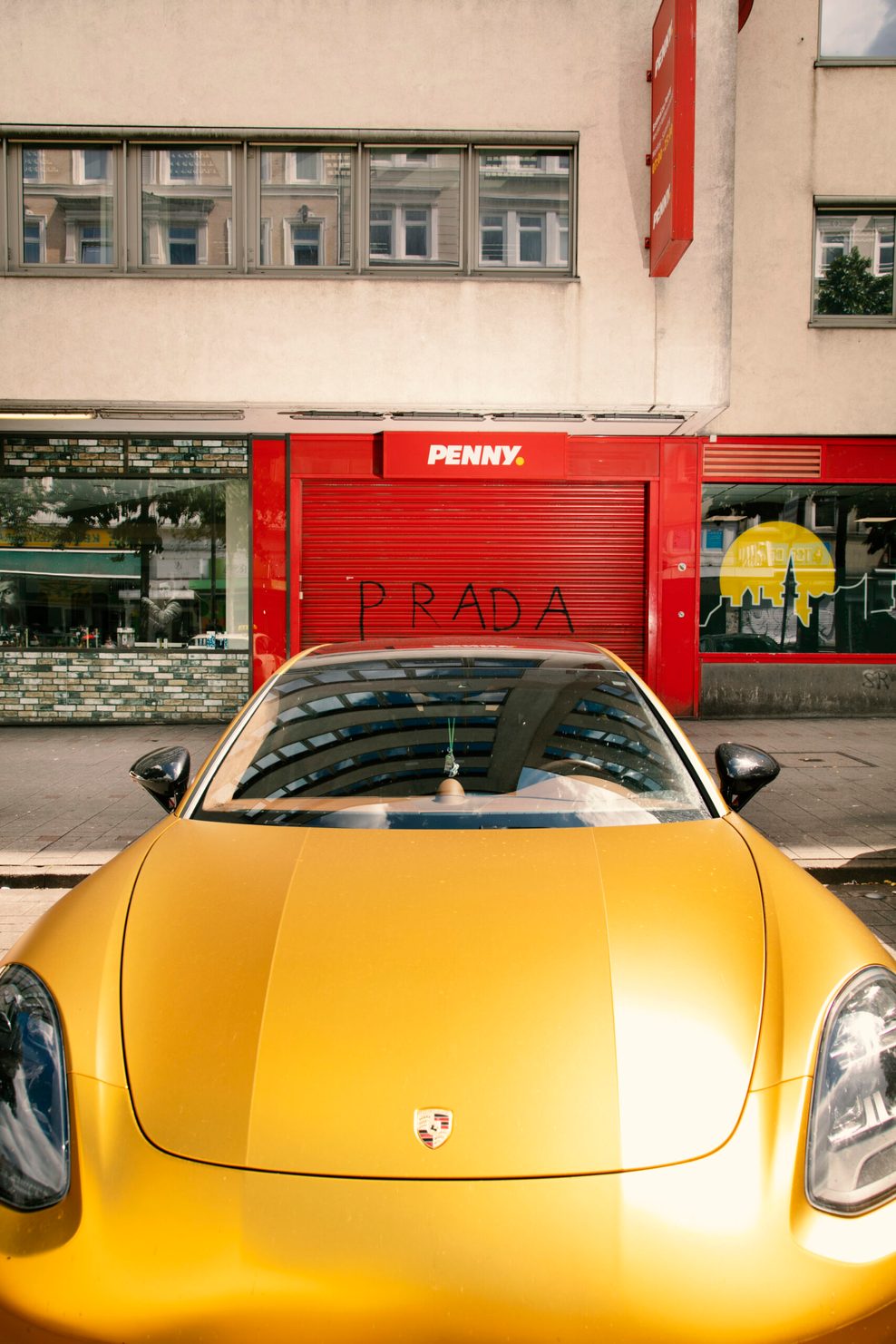 Ein gelber Porsche steht vor dem Eingang eines Penny-Supermarkts