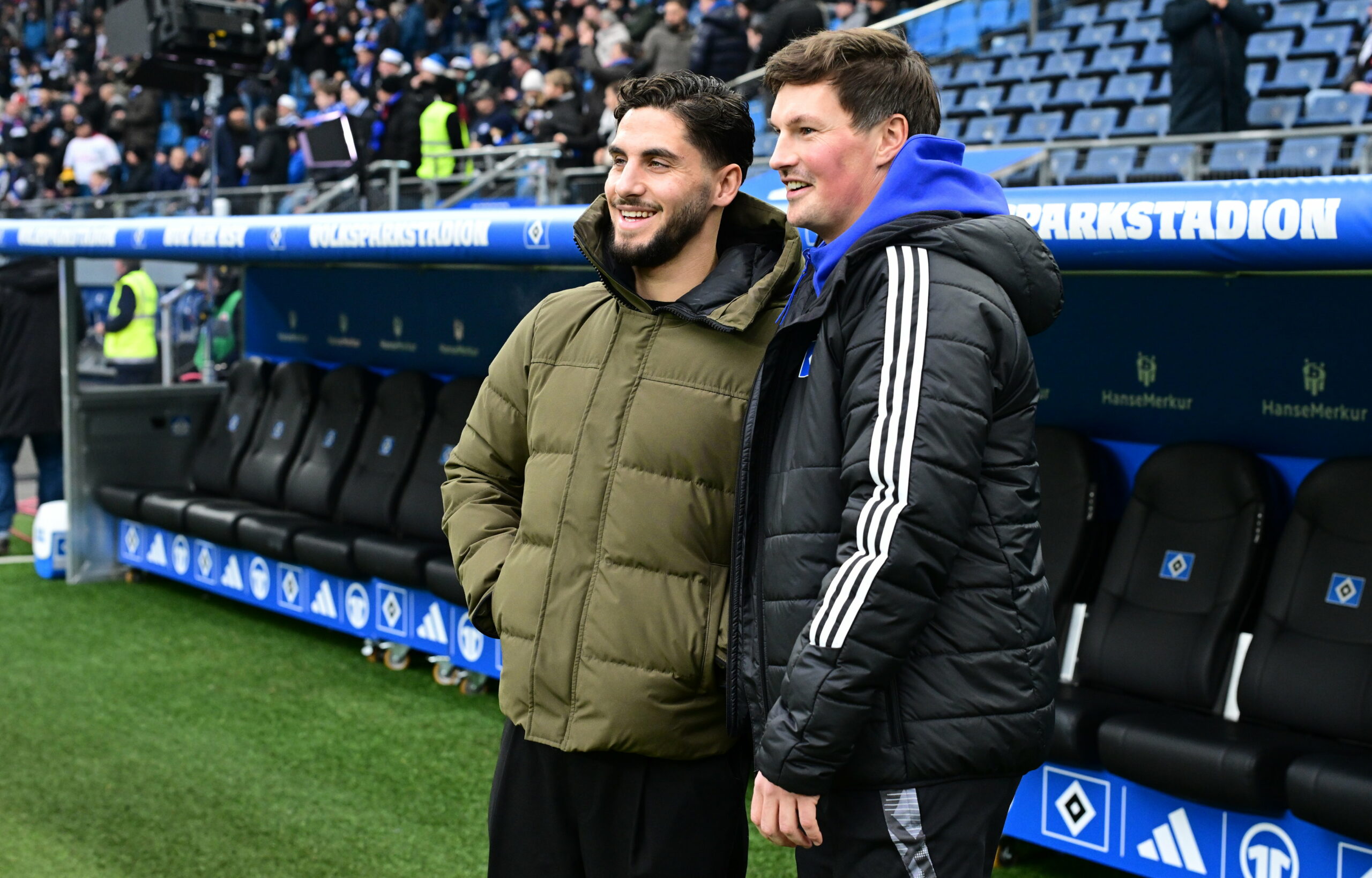 Ludovit Reis lächelt vor der HSV-Bank mit Merlin Polzin