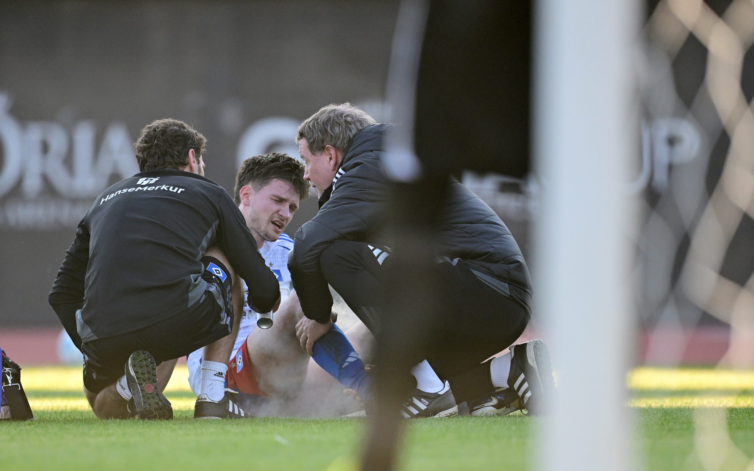 Noah Katterbach wird auf dem Platz von HSV-Betreuern behandelt.