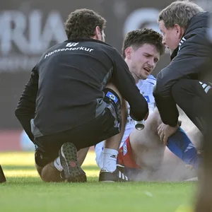 Noah Katterbach wird auf dem Platz von HSV-Betreuern behandelt.