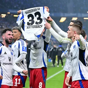 Die Spieler des HSV jubeln und zeigen ein Trikot von Noah Katterbach