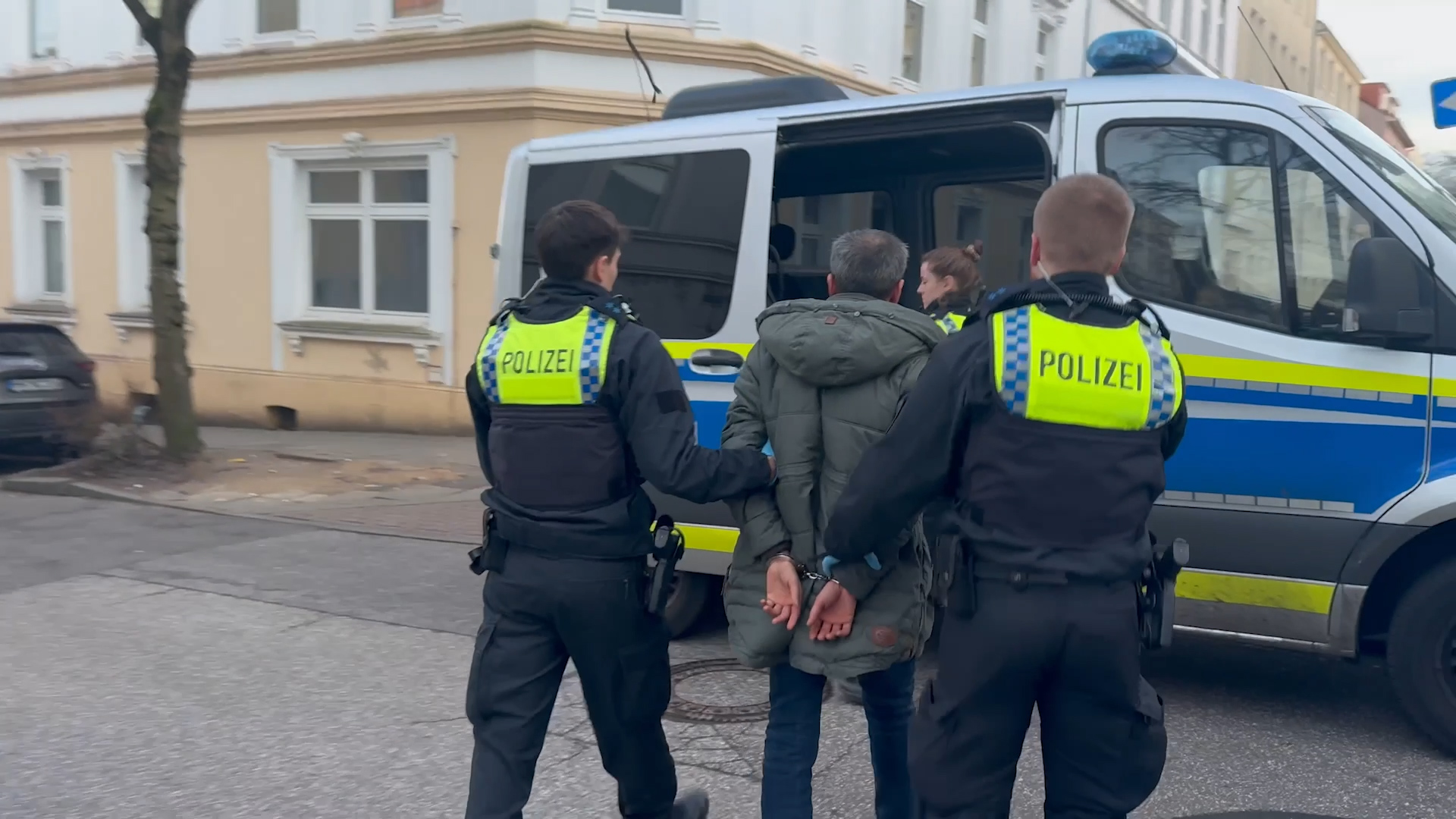 Die Polizei führt einen der Tatverdächtigen ab.