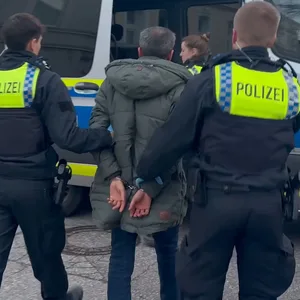 Die Polizei führt einen der Tatverdächtigen ab.