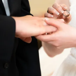 Ein Brautpaar steckt sich während ihrer Trauung die Ringe an.