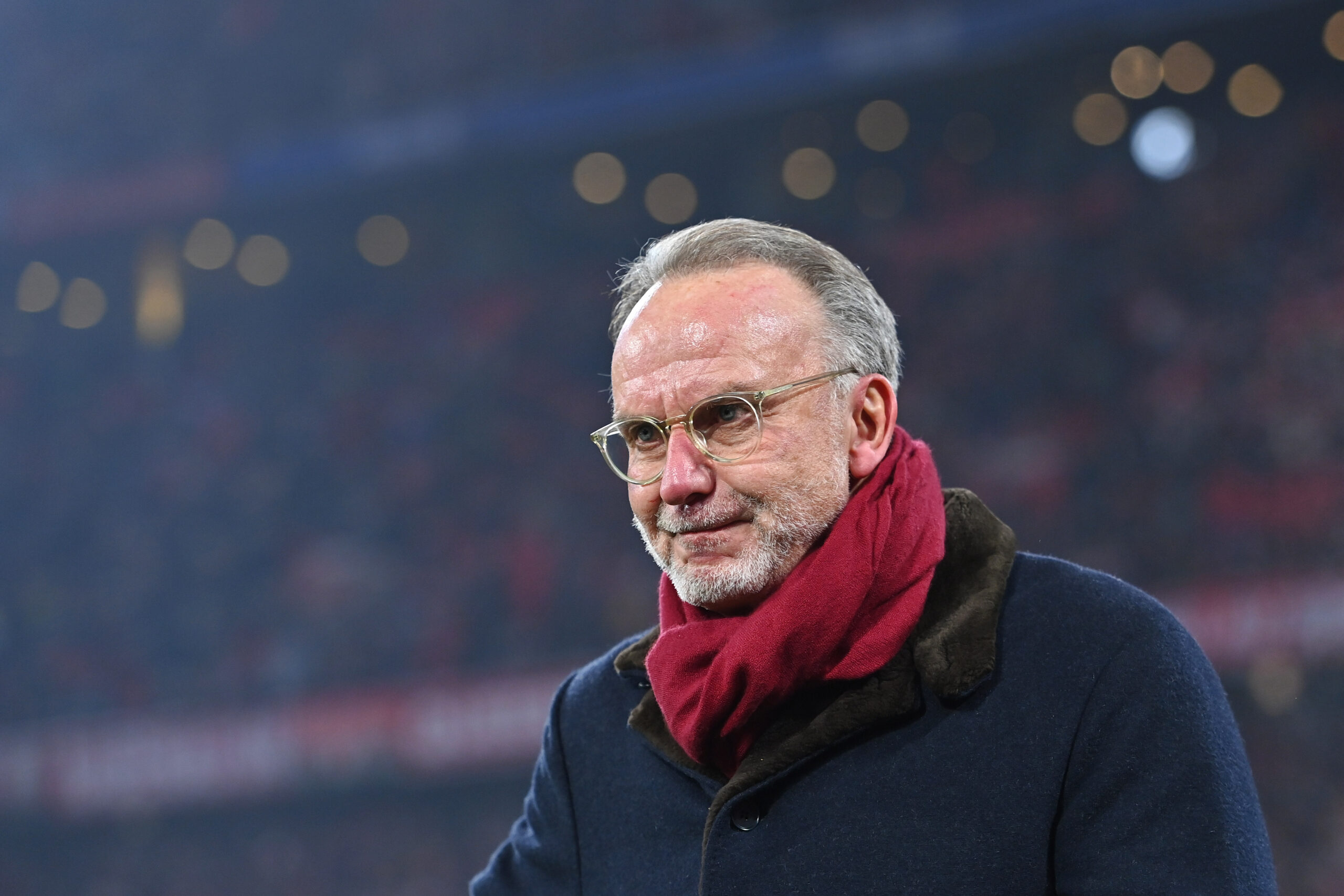 Karl-Heinz Rummenigge trägt einen Mantel und einen roten Schal