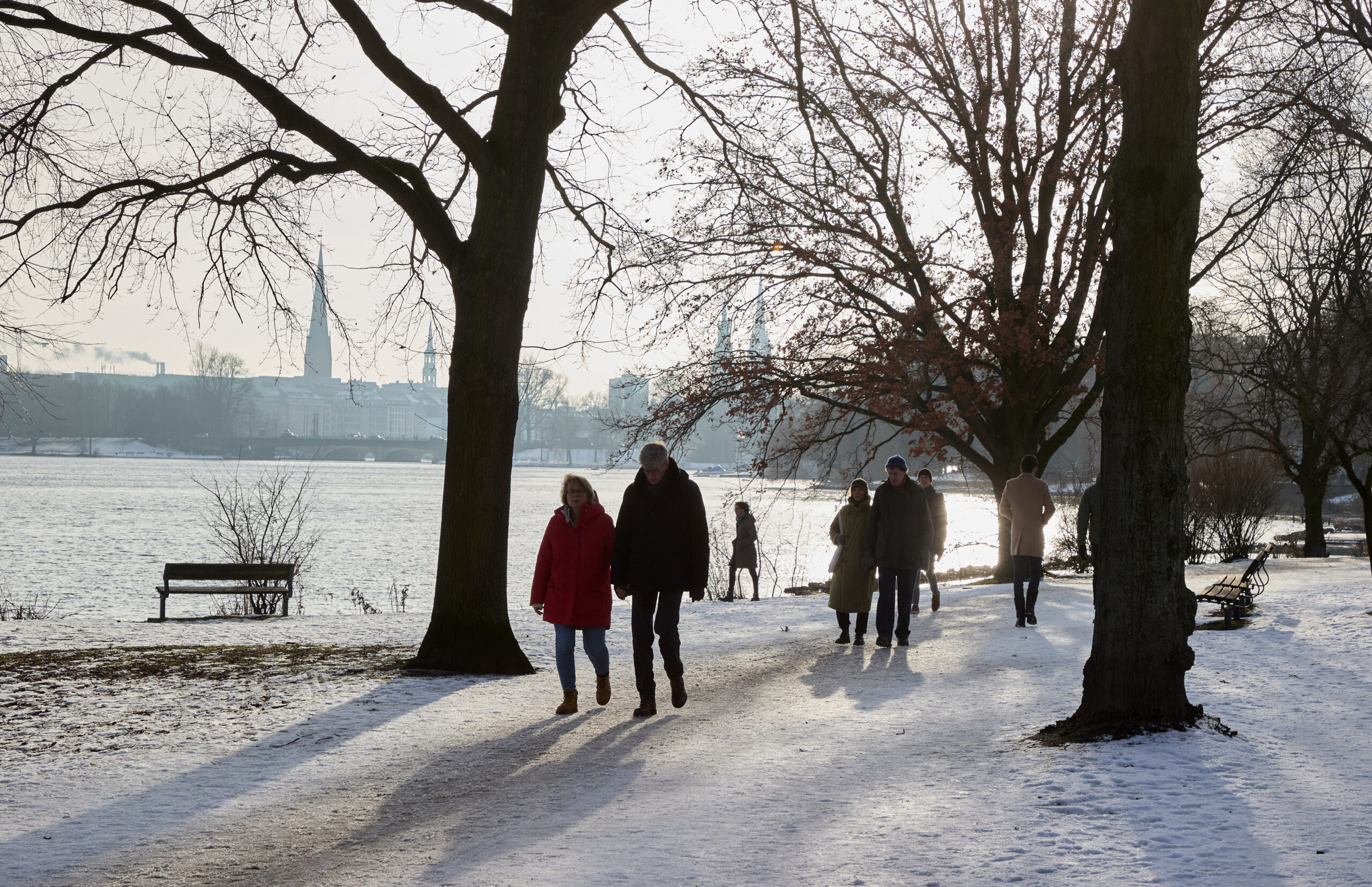 Spaziergänger genießen die Sonnenstrahlen an der Außenalster.