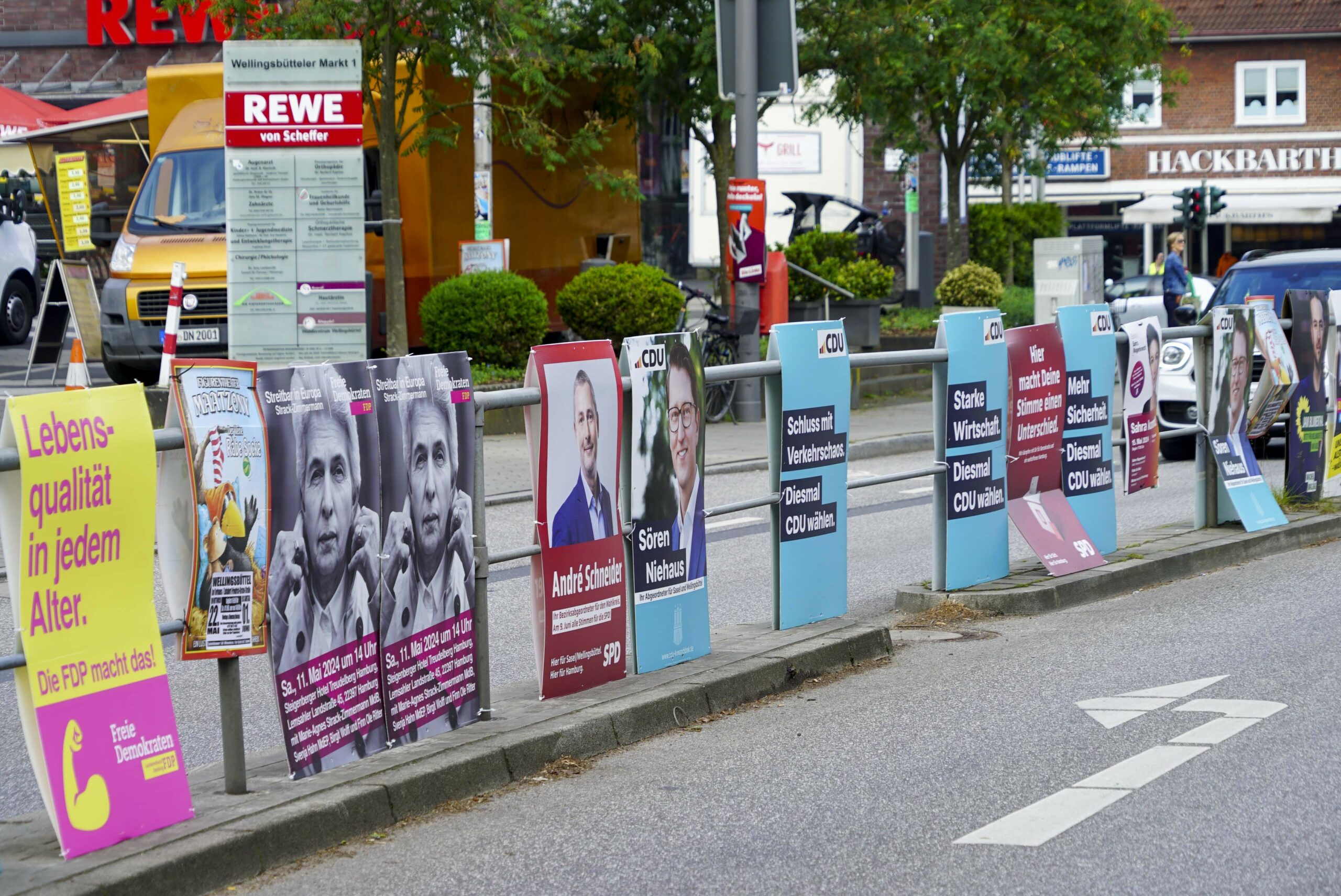 Ein Geländer an einer Straße fast vollständig mit Plakaten behängt